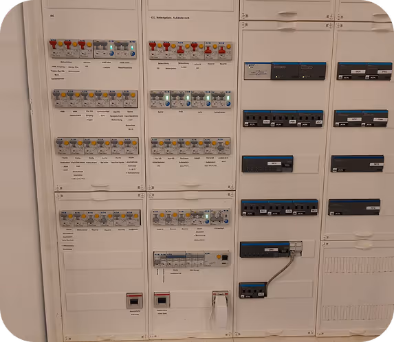 Elektrischer Sicherungskasten mit mehreren Reihen von Sicherungen, Schaltern und Beschriftungen für verschiedene Stromkreise.