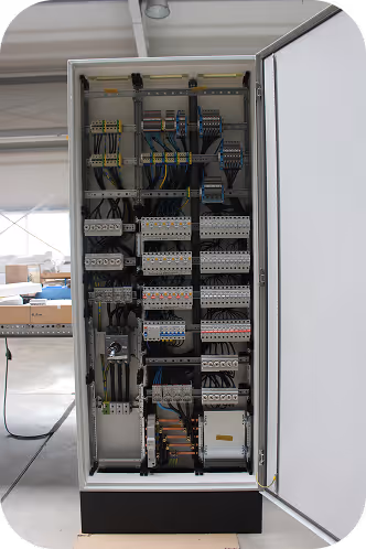 Geöffneter Schaltschrank mit geordneten elektrischen Sicherungen, Leitungen und Komponenten in einer industriellen Umgebung.